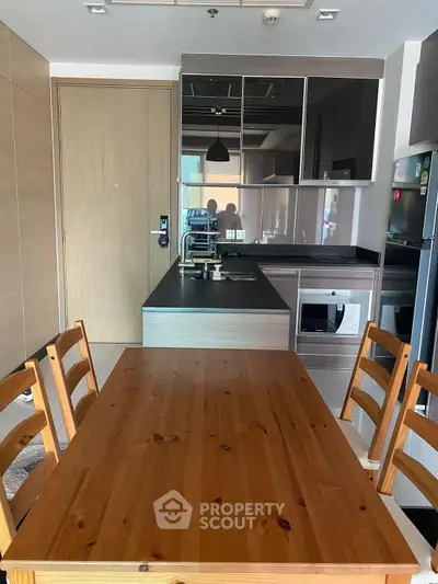 Modern kitchen with wooden dining table and sleek appliances in a stylish apartment.