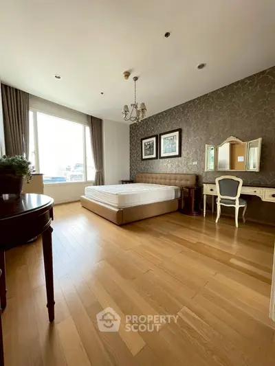 Spacious bedroom with elegant decor and large window offering natural light.