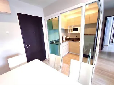 Modern apartment with sleek kitchen and dining area, featuring glass partition and contemporary design.