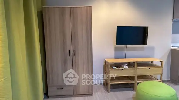 Modern living room with wooden wardrobe and mounted TV, bright and inviting.