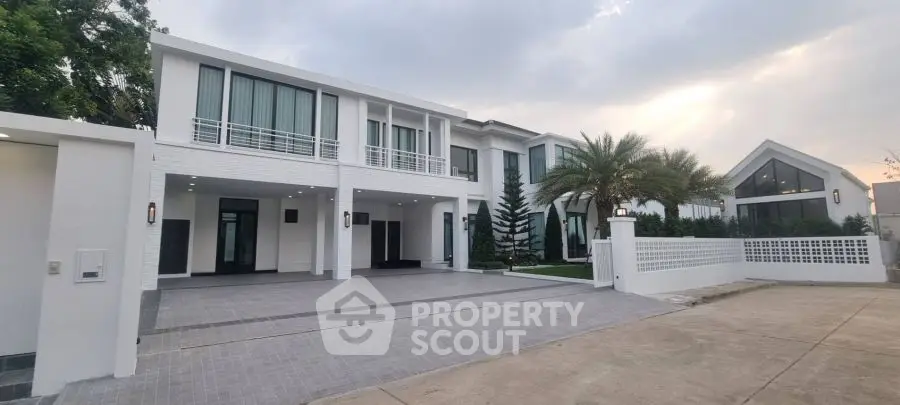 Luxurious modern white villa with spacious driveway and palm trees