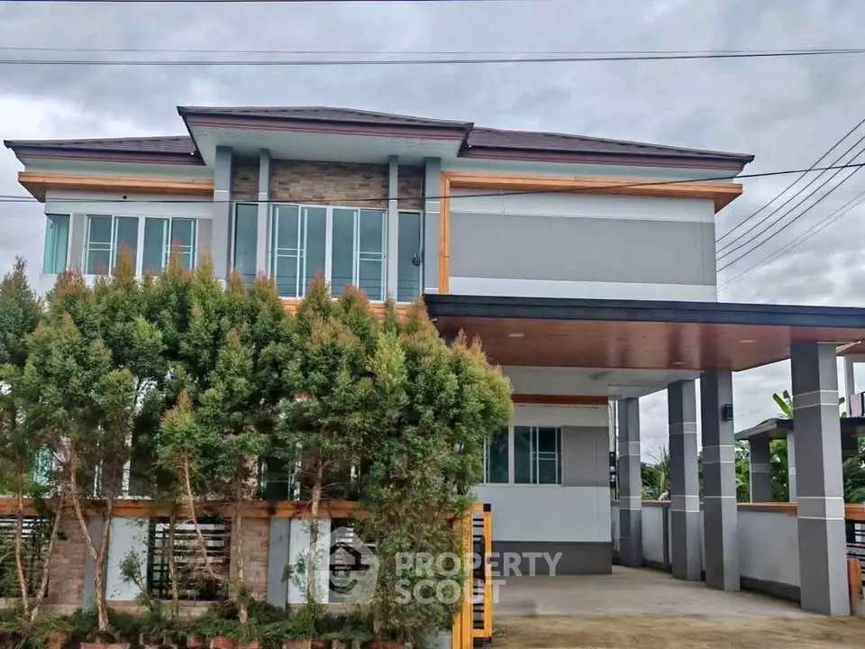 Modern two-story house with sleek design and lush greenery in front yard.