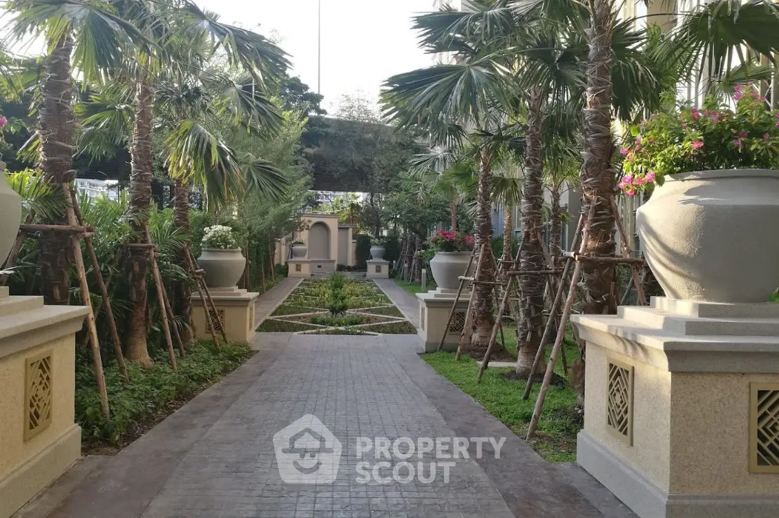 Luxurious garden pathway with lush greenery and elegant planters in a residential complex.