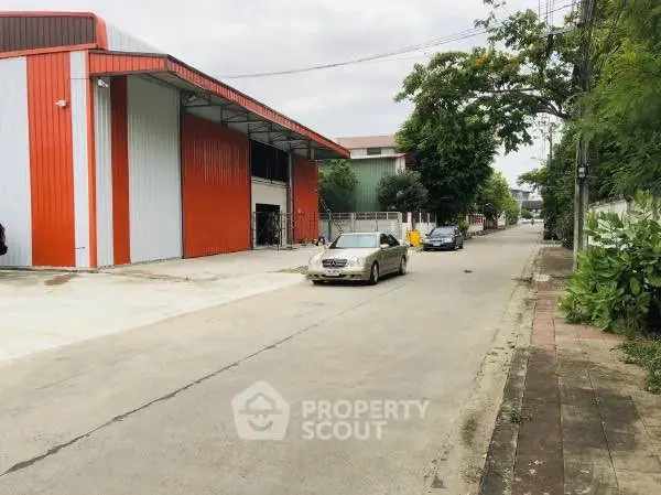 Spacious industrial warehouse with red accents and ample parking space.
