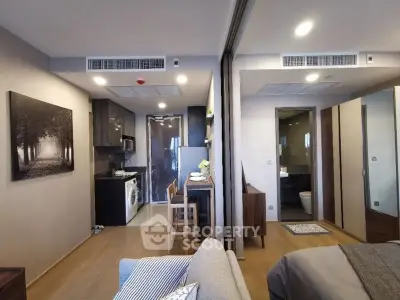 Modern apartment interior with open kitchen and cozy living area, featuring stylish decor and natural lighting.