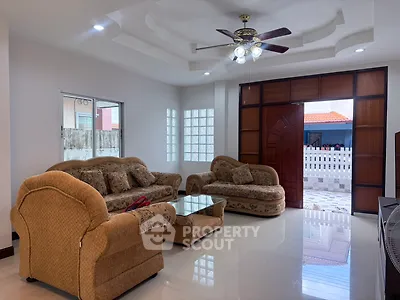 Spacious living room with elegant furniture and ceiling fan, featuring large windows for natural light.