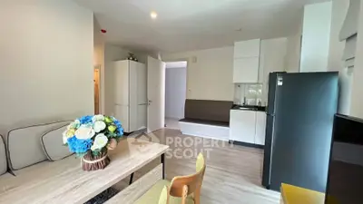 Modern living room with stylish decor and open layout, featuring a cozy seating area and sleek kitchen appliances.