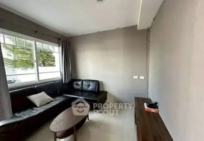 Modern living room with sleek black leather sofa and large window for natural light.