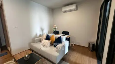 Modern living room with cozy sofa and dining area, featuring elegant decor and air conditioning.