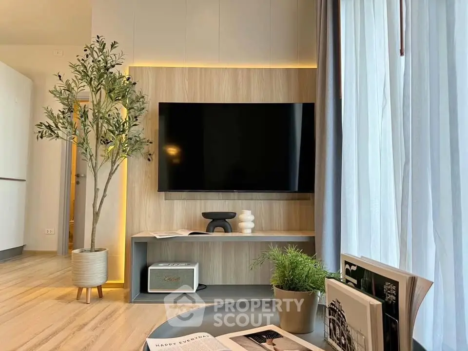 Modern living room with stylish decor, large TV, and natural light from floor-to-ceiling windows.