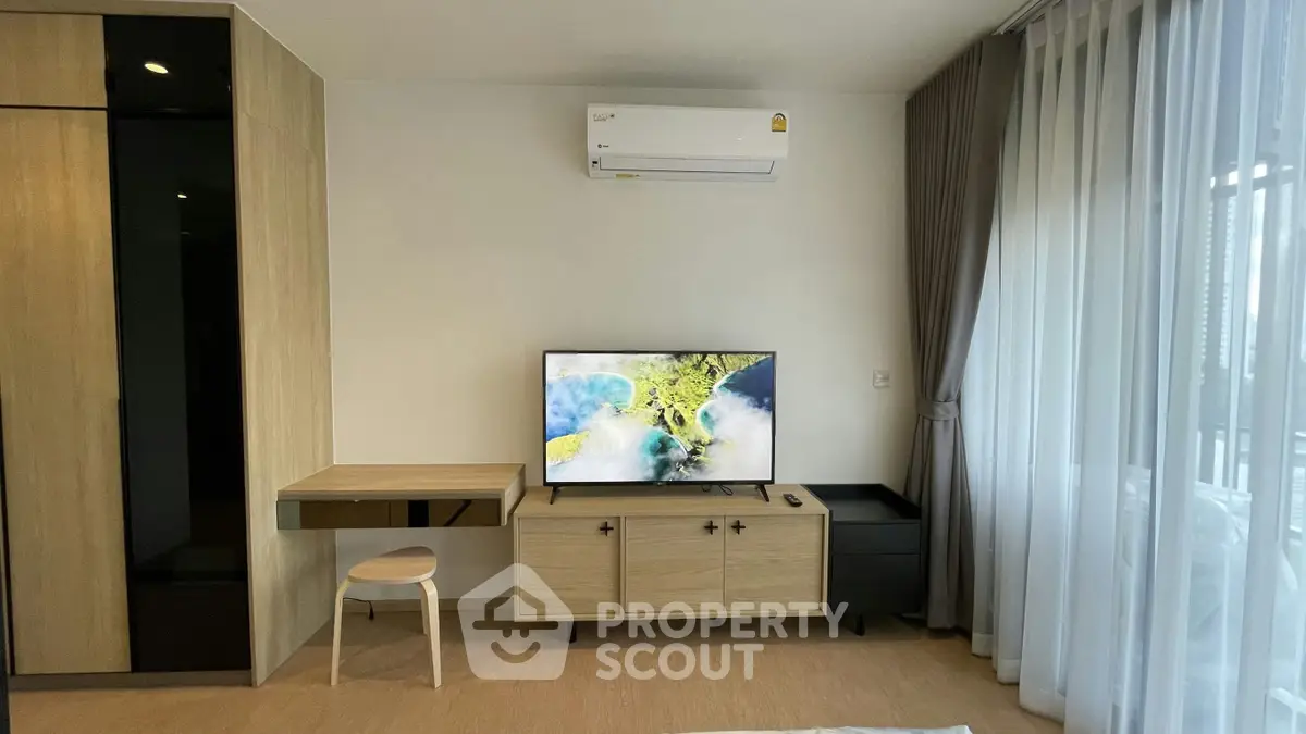Modern living room with sleek furniture, wall-mounted TV, and large window with curtains.