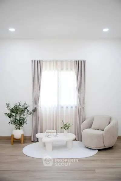 Modern living room with cozy armchair, elegant curtains, and stylish coffee table on wooden flooring.