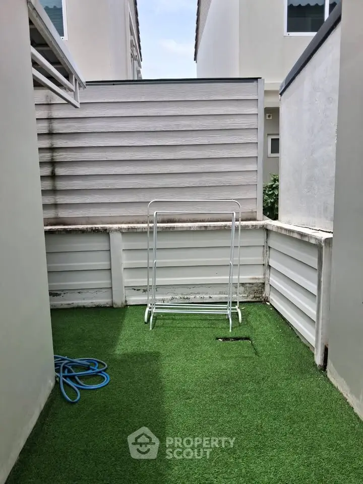 Cozy outdoor space with artificial grass and privacy fencing, perfect for small gatherings or relaxation.