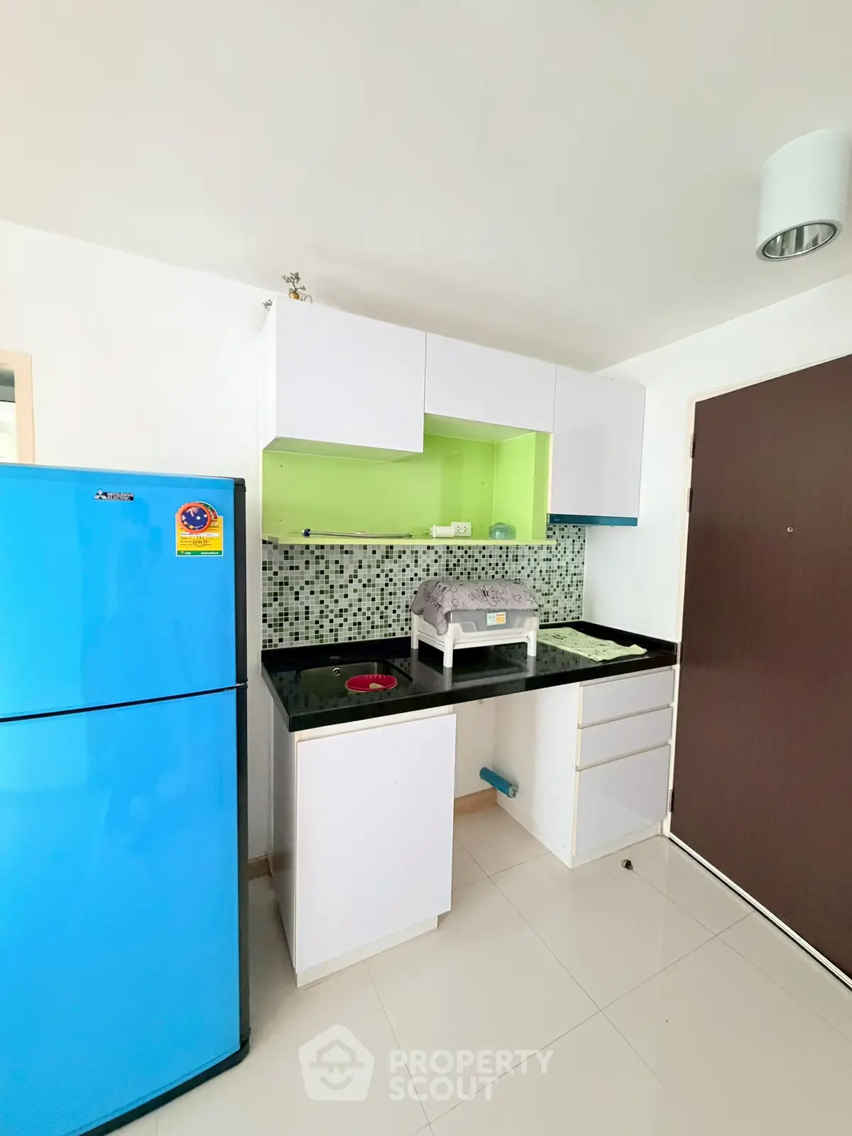 Modern kitchen with vibrant blue fridge and sleek cabinetry in a stylish apartment.