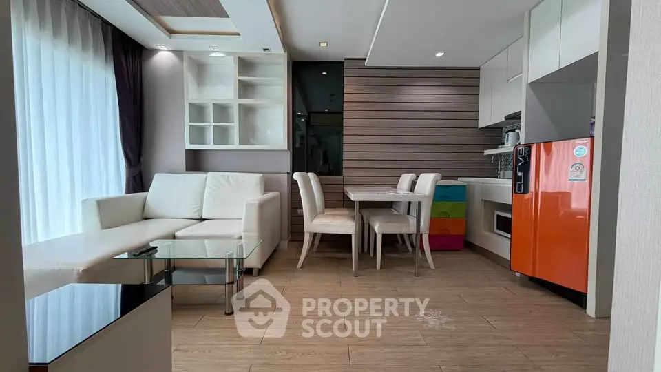 Modern living room with open kitchen, stylish furniture, and bright natural light.