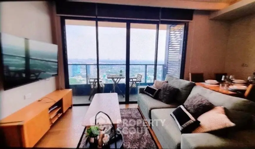 Modern living room with balcony view, stylish furniture, and cozy ambiance in a high-rise apartment.