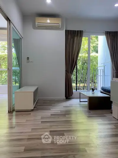 Spacious living room with modern flooring and large windows overlooking greenery.