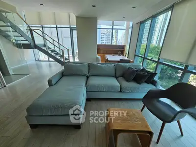 Spacious modern living room with large windows and city view, featuring stylish furniture and open layout.