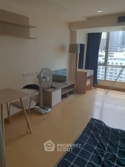 Modern studio apartment with city view, featuring a cozy living area and stylish furnishings.