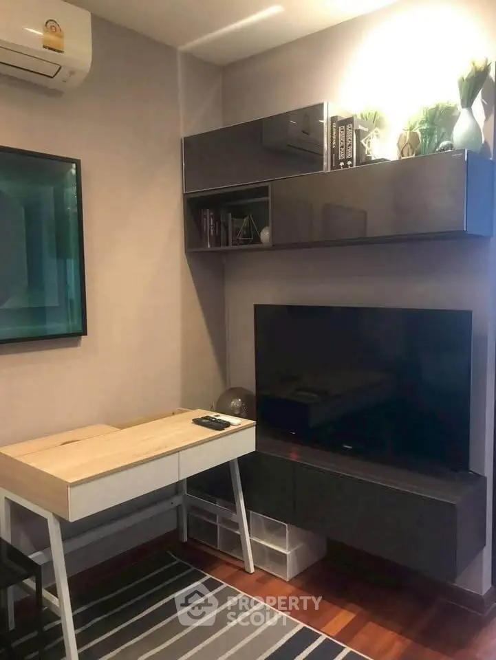 Modern living room with sleek TV setup and stylish desk, perfect for urban living.