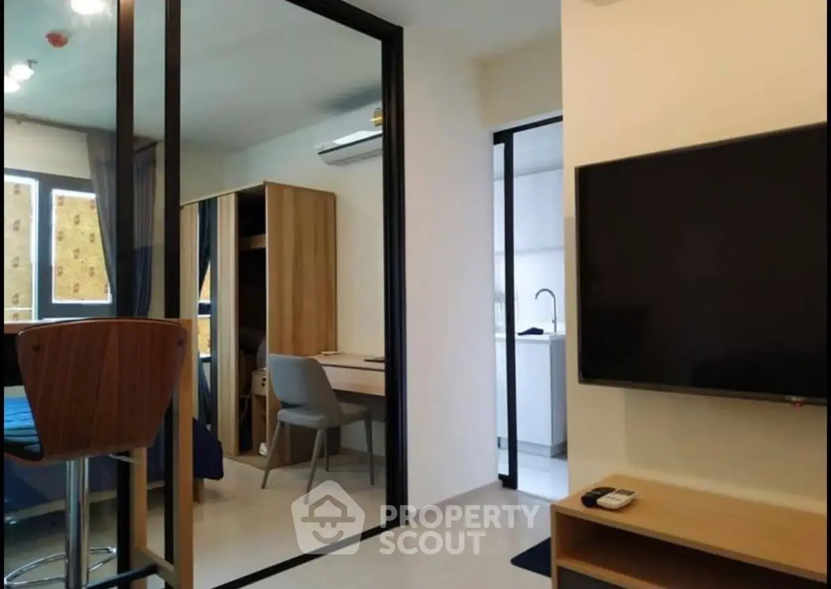 Modern apartment interior with sleek furniture and open layout, featuring a cozy study area and large TV.