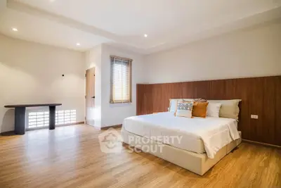 Spacious modern bedroom with wooden flooring and stylish decor