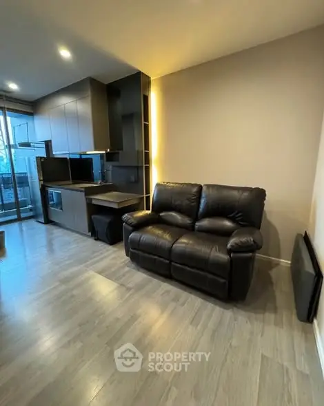 Modern apartment with sleek kitchen and cozy living area featuring a leather sofa.