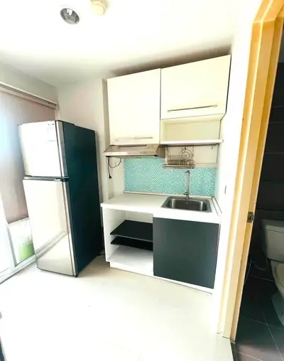 Compact modern kitchen with sleek cabinetry and stainless steel fridge