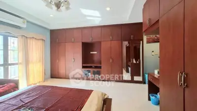 Spacious bedroom with built-in wooden wardrobes and large windows for natural light.