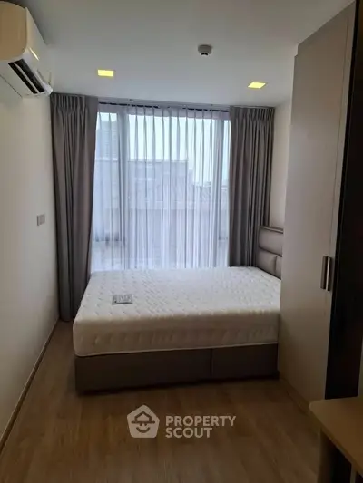 Modern bedroom with large window and stylish furnishings in a high-rise apartment.