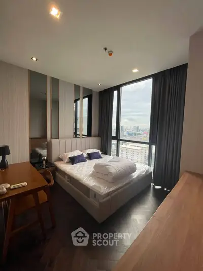 Modern bedroom with city view, featuring stylish decor and large windows for natural light.