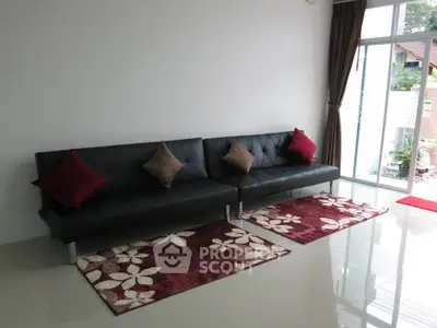 Modern living room with sleek black sofa and stylish red accents.