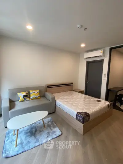 Modern studio apartment with cozy bed and stylish sofa in open layout.