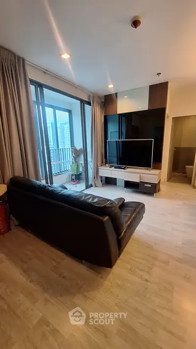 Modern living room with sleek black sofa and city view balcony.