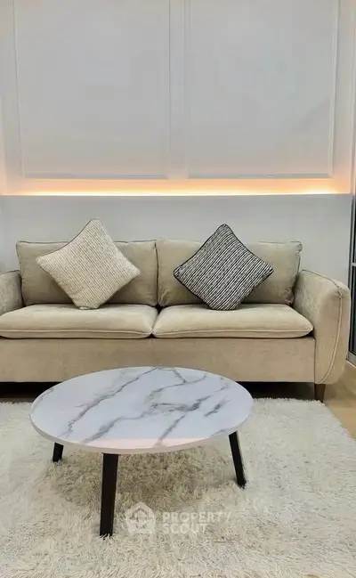 Elegant living room with cozy beige sofa and stylish marble coffee table on plush rug.
