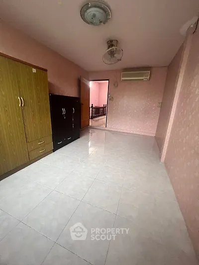 Spacious bedroom with pink walls, air conditioning, and ample storage space.