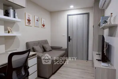 Modern living room with cozy sofa, desk, and wall art in a compact apartment.