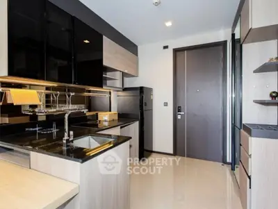 Modern kitchen with sleek black and wood cabinetry, featuring a built-in oven and spacious countertops.