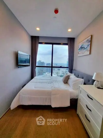 Modern bedroom with city view, featuring cozy bed and stylish decor.