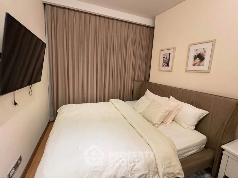 Cozy bedroom with modern decor and wall-mounted TV, perfect for relaxation.