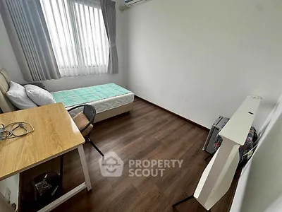 Cozy minimalist bedroom with wooden flooring and ample natural light.