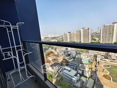 Stunning high-rise balcony view overlooking cityscape with modern buildings and clear blue sky.