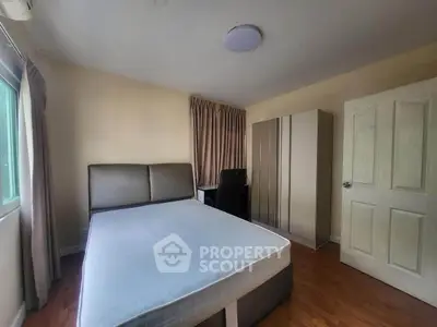Cozy bedroom with natural light, featuring a comfortable bed and modern wardrobe.