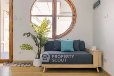 Stylish living room with modern sofa and circular window, perfect for relaxation.