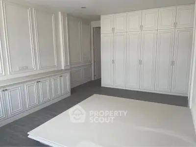 Spacious room with elegant white cabinetry and modern flooring, perfect for versatile use.