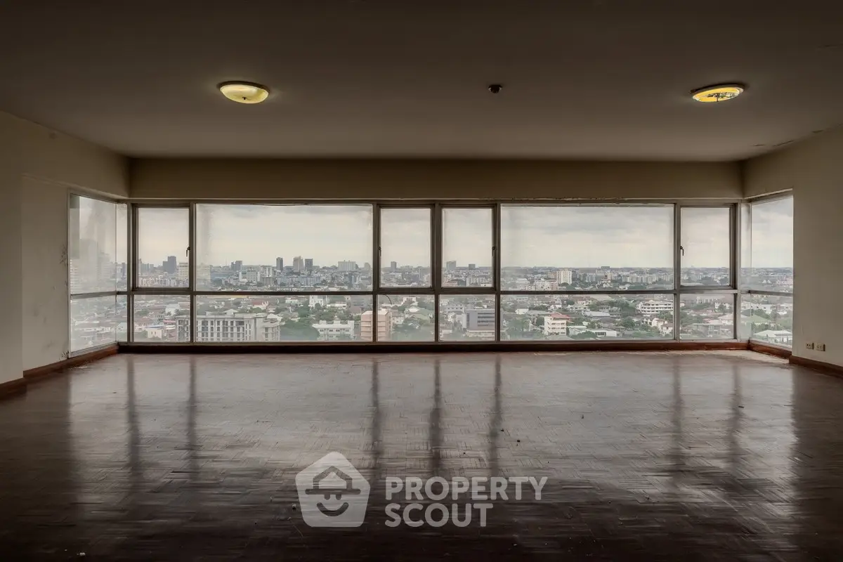 Spacious empty living room with panoramic city view through large windows.