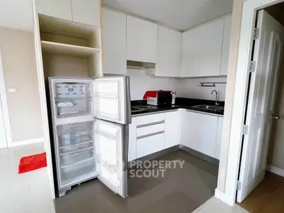 Modern kitchen with open fridge and sleek cabinetry in a stylish apartment.