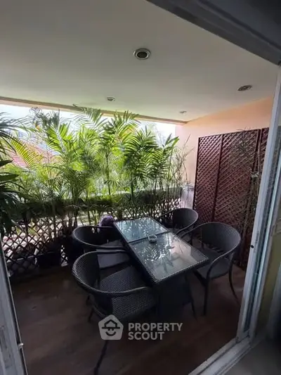 Charming balcony with lush greenery and cozy seating area, perfect for relaxation and outdoor dining.