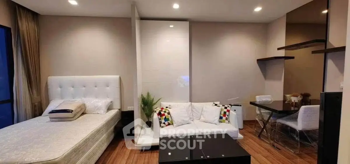 Modern studio apartment with cozy bed, stylish sofa, and elegant dining area.