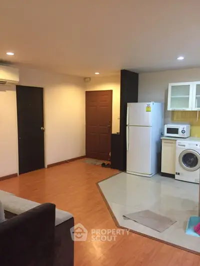 Spacious open-plan living room with kitchen featuring modern appliances and wooden flooring.